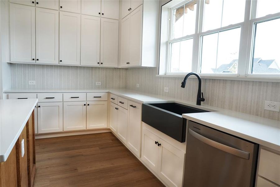 Kitchen featuring dishwasher, dark hardwood / wood-style flooring, white cabinets, and sink