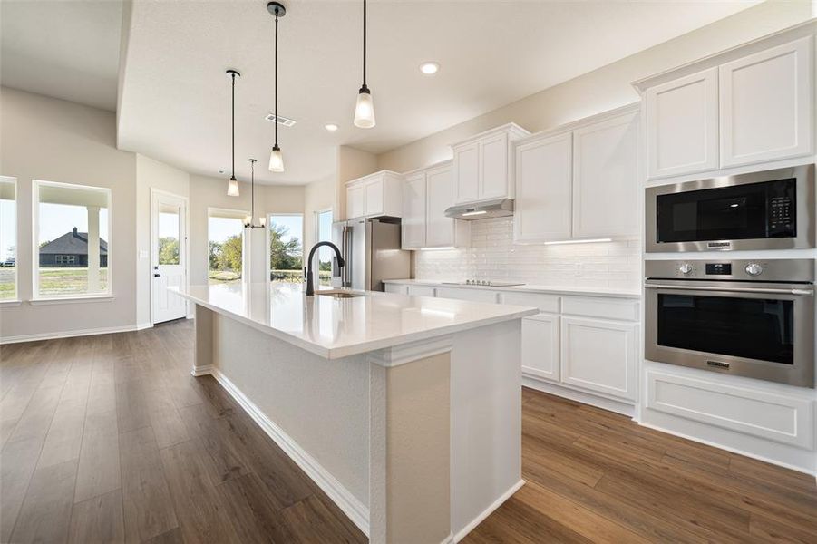 Kitchen with stainless steel appliances, backsplash, white cabinets, hanging light fixtures, and recessed lighting