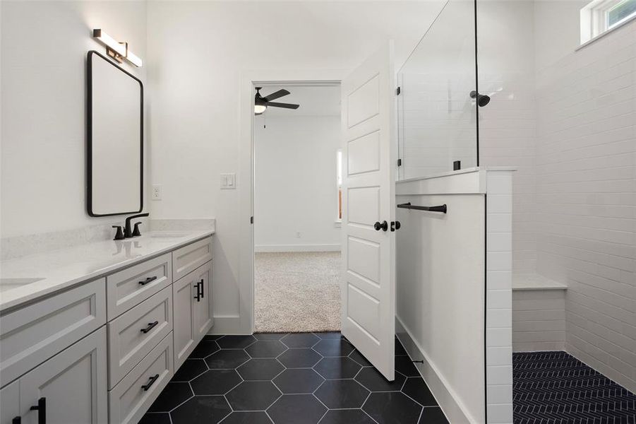 Bathroom featuring a tile shower, tile patterned floors, double sink vanity, and ceiling fan