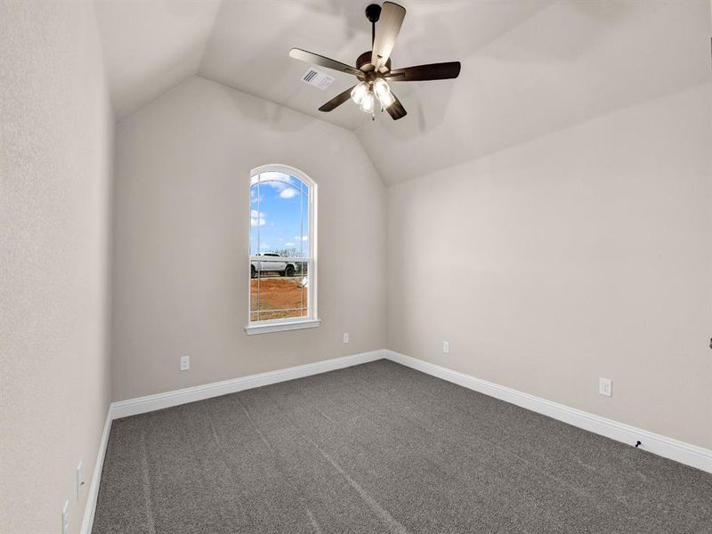 Carpeted spare room with ceiling fan and vaulted ceiling