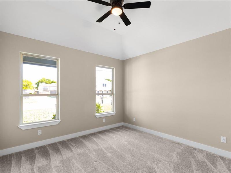 Carpeted empty room featuring ceiling fan and lofted ceiling