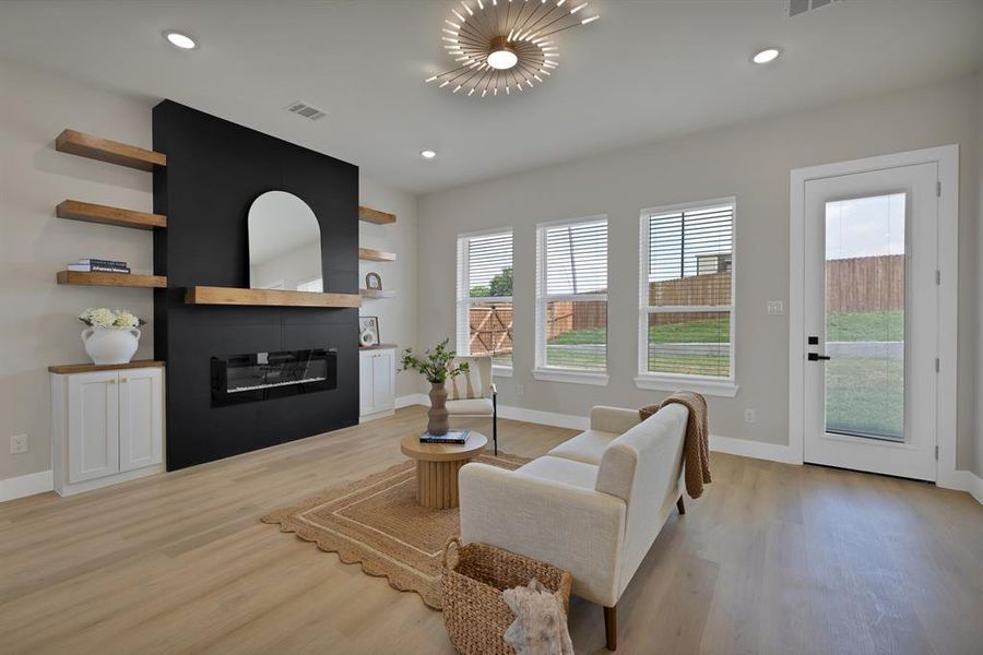 Living room featuring a glass covered fireplace, light wood-type flooring, baseboards, and recessed lighting Living room featuring a glass covered fireplace, light wood-type flooring, baseboards, and recessed lighting