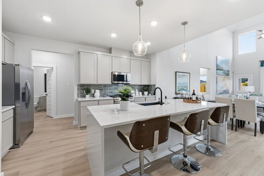 Modern kitchen featuring a white quartz island with seating, gray tile backsplash, and pendant lights Modern kitchen featuring a white quartz island with seating, gray tile backsplash, and pendant lights