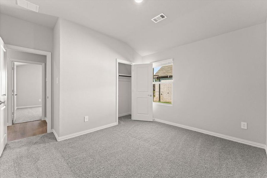 Unfurnished bedroom featuring a closet, lofted ceiling, and carpet flooring