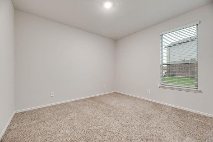 Neutral-toned room featuring light beige carpeting, white walls, and a single window with blinds