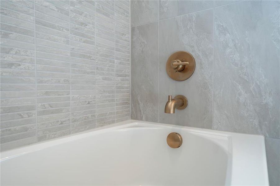 More gold plumbing fixtures in the bathtub/shower in the guest bathroom