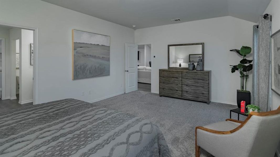 Bedroom with ensuite bath, light colored carpet, and lofted ceiling
