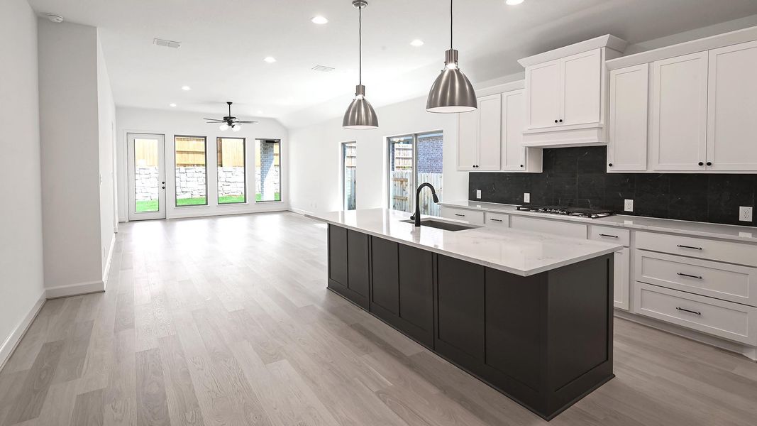Kitchen with white cabinets, backsplash, a center island with sink, decorative light fixtures, and recessed lighting Kitchen with white cabinets, backsplash, a center island with sink, decorative light fixtures, and recessed lighting