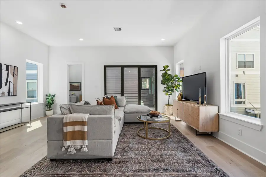 Framed by expansive windows and sliding glass doors, the living area is filled with natural light and warmth. Light wood floors and crisp white walls enhance the airy atmosphere, while recessed lighting adds a modern touch. The space flows seamlessly into the adjacent areas, offering an ideal layout for both relaxation and entertaining. Framed by expansive windows and sliding glass doors, the living area is filled with natural light and warmth. Light wood floors and crisp white walls enhance the airy atmosphere, while recessed lighting adds a modern touch. The space flows seamlessly into the adjacent areas, offering an ideal layout for both relaxation and entertaining.