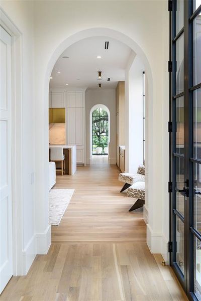 Hallway featuring arched walkways, light wood-style flooring, and recessed lighting Hallway featuring arched walkways, light wood-style flooring, and recessed lighting