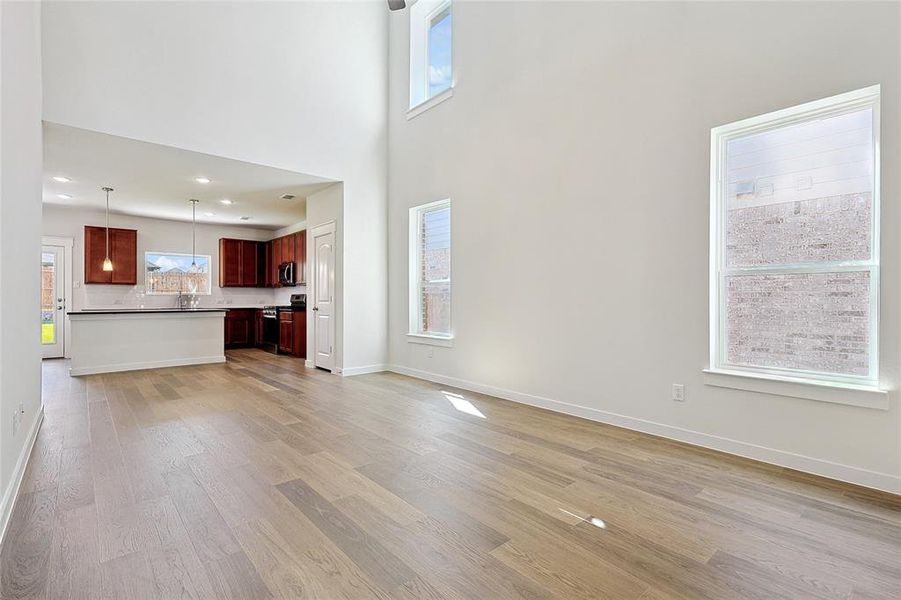 Unfurnished living room with light wood-type flooring, a high ceiling, and plenty of natural light