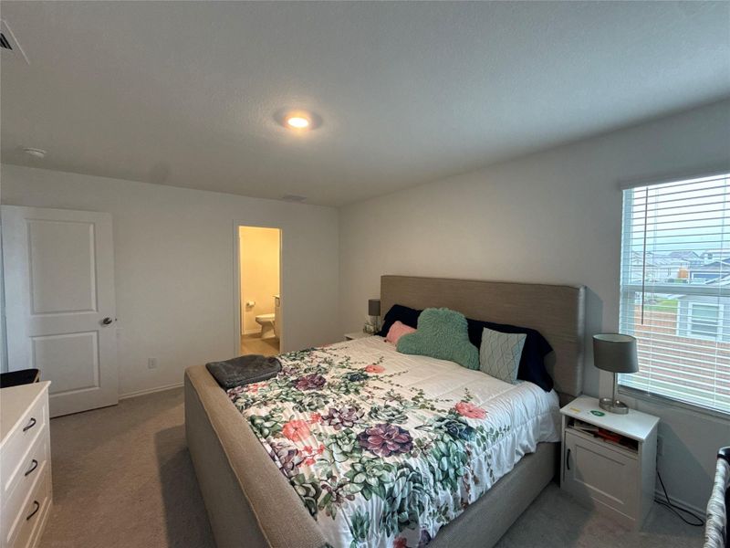 Carpeted room with a window featuring blinds, a recessed ceiling light, and a door leading to a bathroom