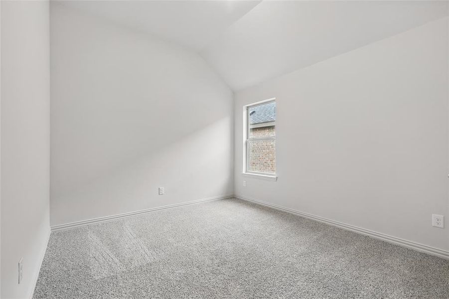 Carpeted spare room with vaulted ceiling and baseboards