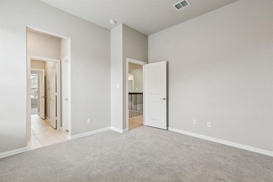 Unfurnished bedroom with light carpet and baseboards