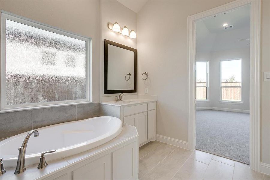 Bathroom with tile patterned floors, vanity, and a washtub