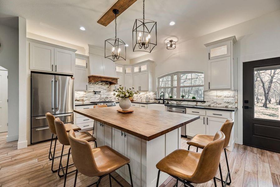 Look at this Stunningly Beautiful Kitchen! Custom lighting throughout the cabinets, above, inset and under. Black Leathered Granite countertops, Quartz backsplash, butcher block island topper, pot filler, gas cook top and range and more!
