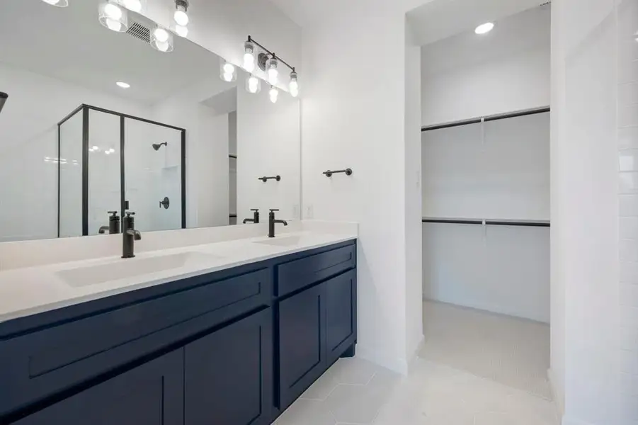 Bathroom featuring a double vanity with dark cabinetry and white countertops