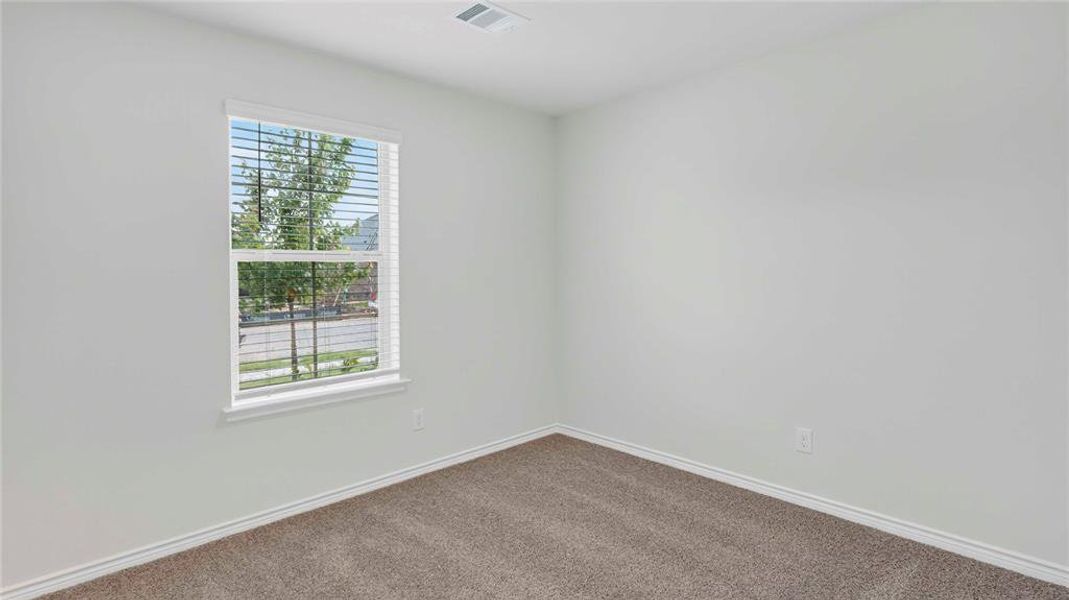 Bright room featuring a window with white blinds, neutral carpeting, white walls, and white baseboards