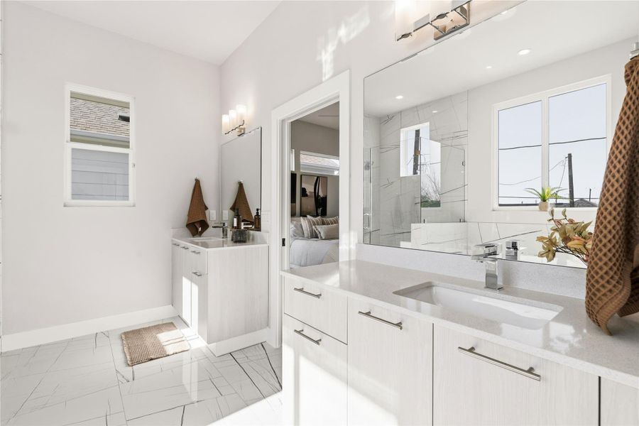 Separated vanities create defined personal space, allowing each side to function independently without compromise. Generous storage is built in, while large windows flood the bath with natural light, keeping the space bright, calm, and highly functional from morning to night.