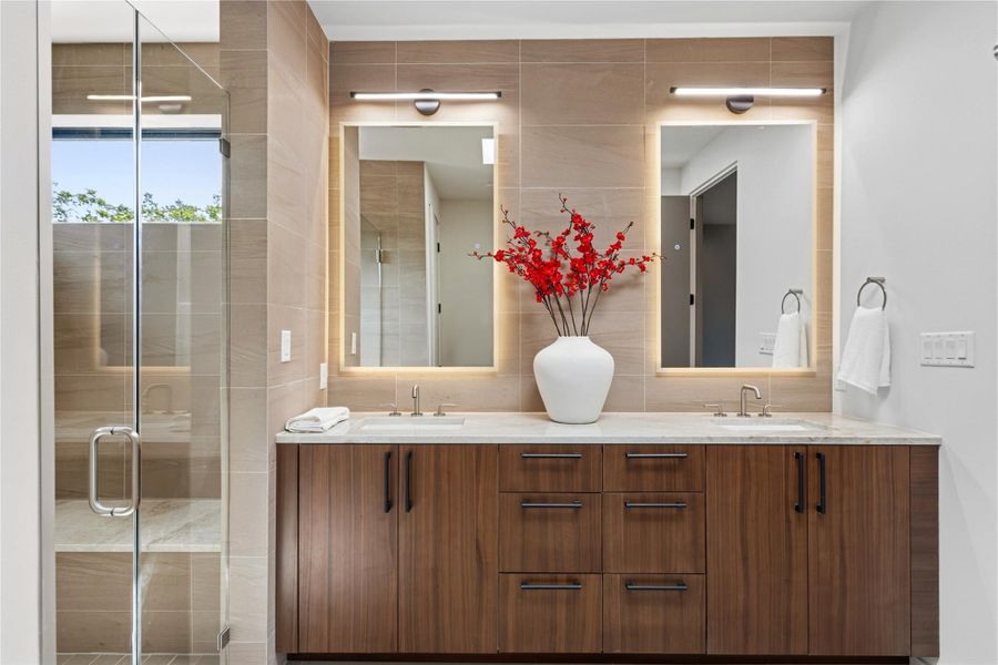 Custom cabinetry and elegant vanity lighting elevate this spa-like primary bath experience.