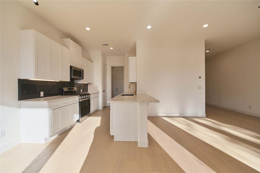 Kitchen featuring light hardwood / wood-style floors, white cabinetry, sink, and stainless steel appliances