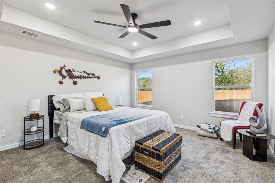 Carpeted bedroom featuring a tray ceiling, ceiling fan, and recessed lighting