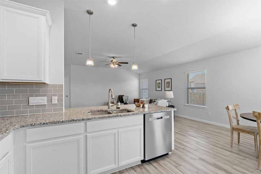 Kitchen featuring white cabinetry, open floor plan, light wood-type flooring, dishwasher, and lofted ceiling