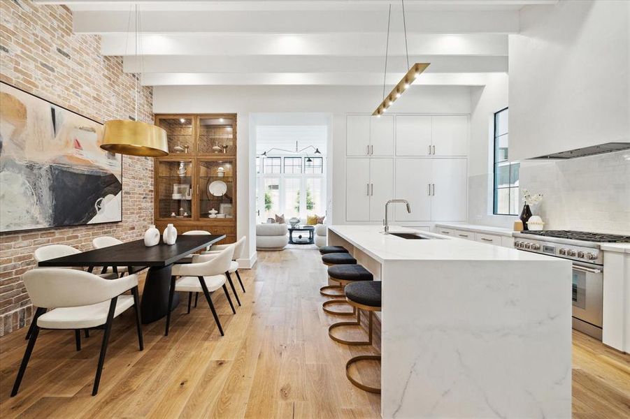 Enjoy lavish dinner parties in the impeccable dining room, featuring Visual Comfort lighting, custom rift white oak built-in cabinetry and a stunning brick wall.