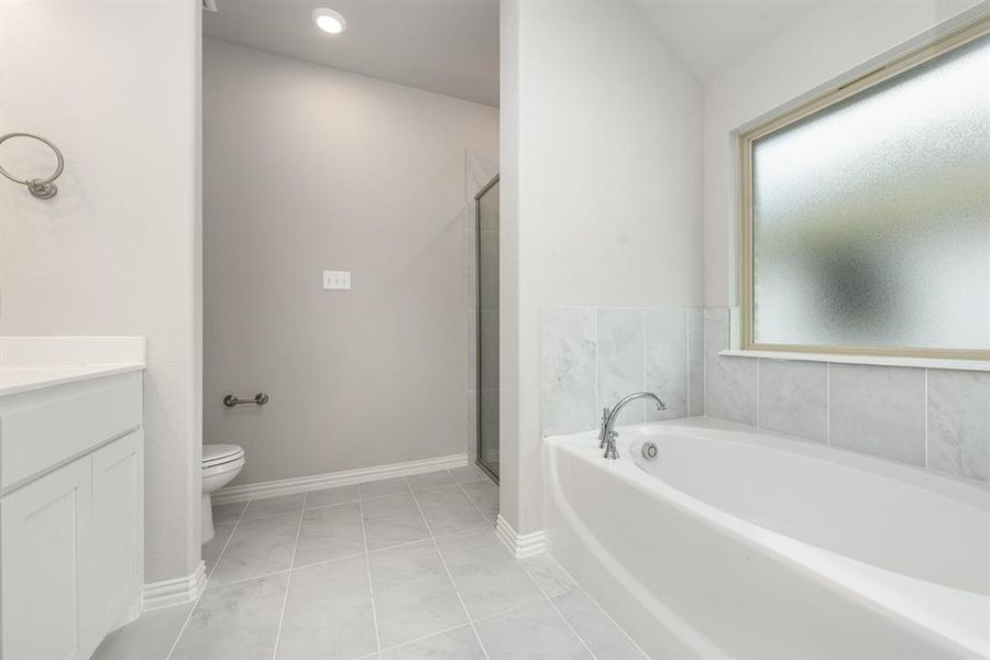 Full bathroom with tile patterned floors, toilet, vanity, and plenty of natural light