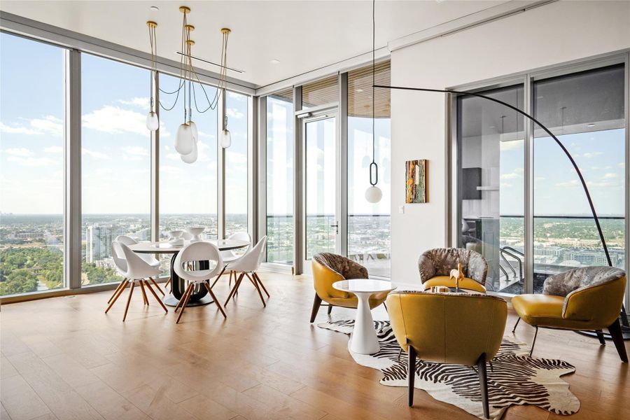This contemporary modern high-rise dining area boasts floor-to-ceiling windows with sweeping cityscape views, complemented by a striking, one-of-a-kind chandelier.