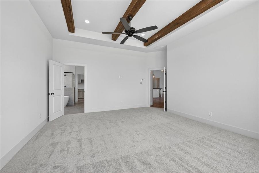 Unfurnished bedroom featuring recessed lighting, ceiling fan, light colored carpet, a tray ceiling, and beam ceiling