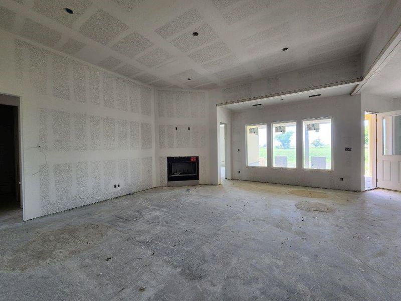 Spacious interior room featuring a built-in fireplace, multiple windows, a recessed ceiling element, and an open doorway