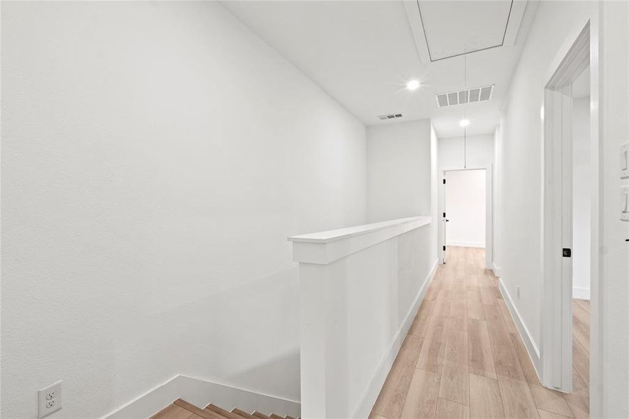 Hall featuring attic access, baseboards, an upstairs landing, light wood-type flooring, and recessed lighting Hall featuring attic access, baseboards, an upstairs landing, light wood-type flooring, and recessed lighting