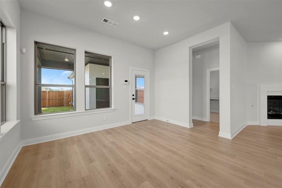 Unfurnished living room with a glass covered fireplace, light wood finished floors, and recessed lighting