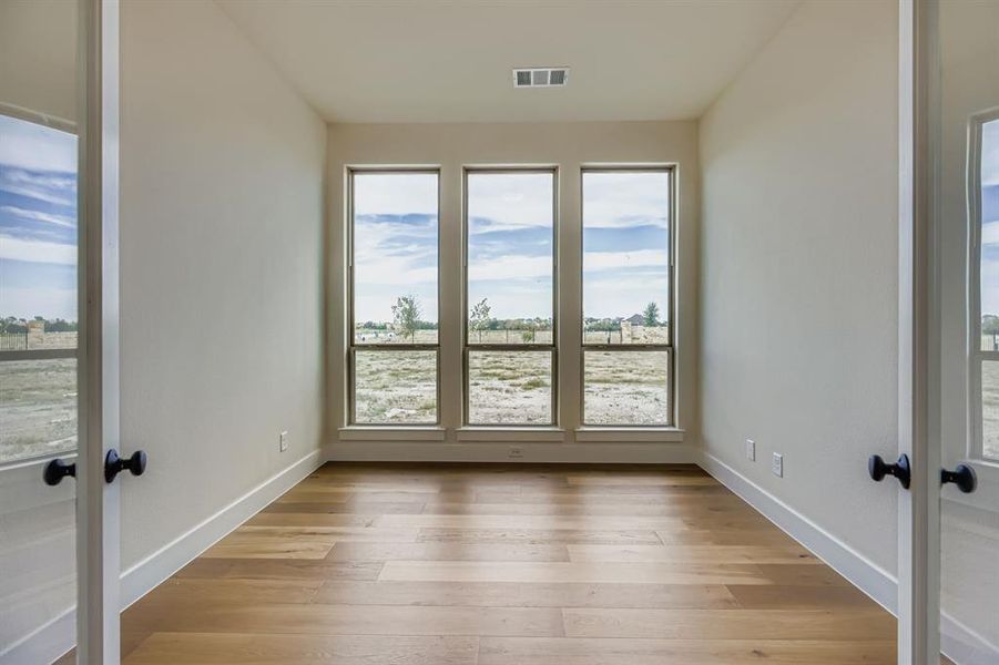 Empty room with light wood-style floors and french doors Empty room with light wood-style floors and french doors