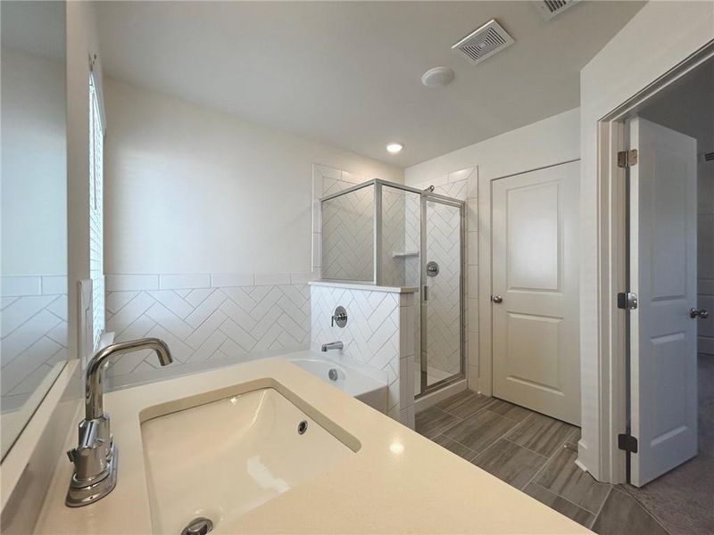 Bathroom with tile flooring, sink, and shower with separate bathtub