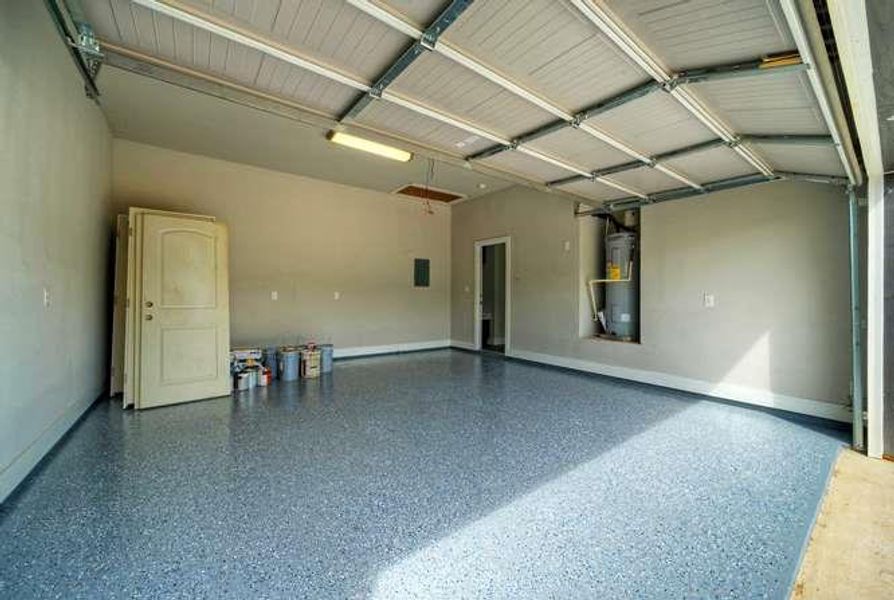A spacious, newly finished garage with a speckled blue floor and ample storage potential.