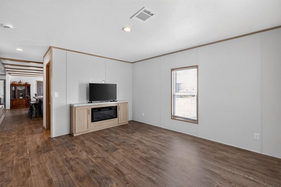 A welcoming living room featuring rich wood flooring and a modern entertainment unit with an electric fireplace.