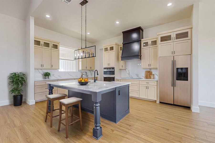 Kitchen featuring light hardwood / wood-style flooring, black appliances, light stone counters, and a center island with sink