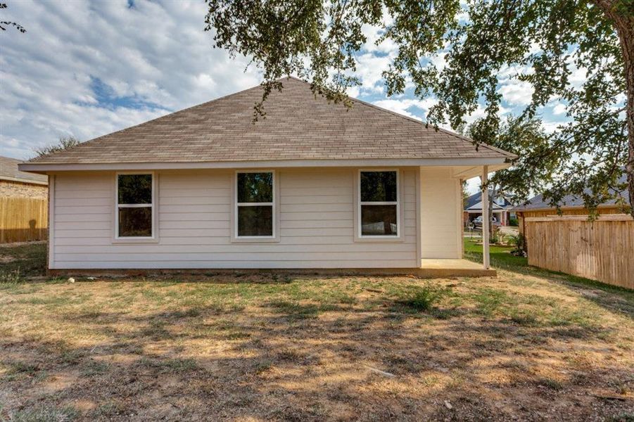 Back of property with a shingled roof and a patio