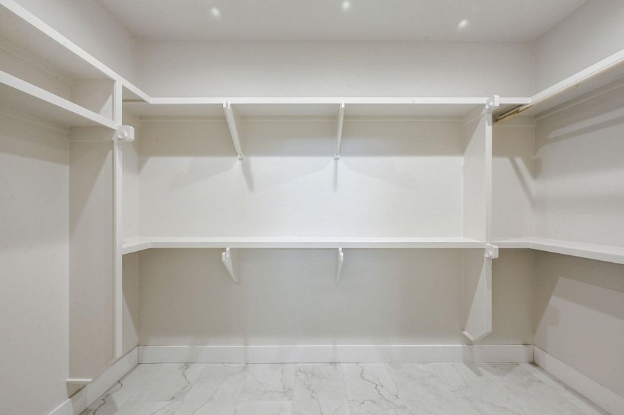 Expansive closet with built-in shelving and hanging space, finished in bright white for clean visibility and organization. Expansive closet with built-in shelving and hanging space, finished in bright white for clean visibility and organization.