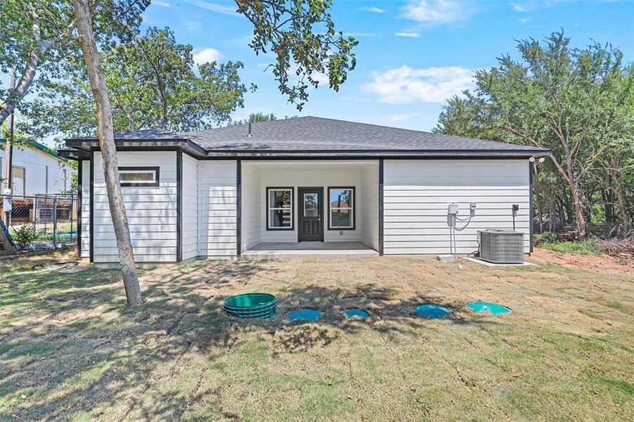 Rear view of house featuring central air condition unit, french doors, and a lawn