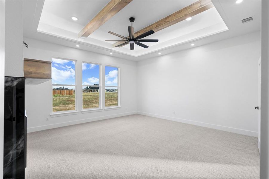 Unfurnished living room featuring sink, ceiling fan, a premium fireplace, beam ceiling, and light colored carpet