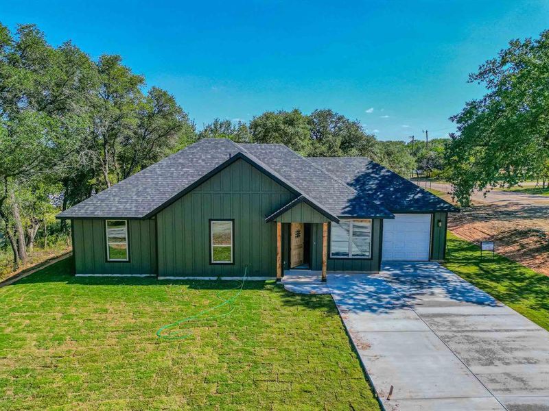 View of front of home with board and batten siding, a shingled roof, driveway, and a front yard