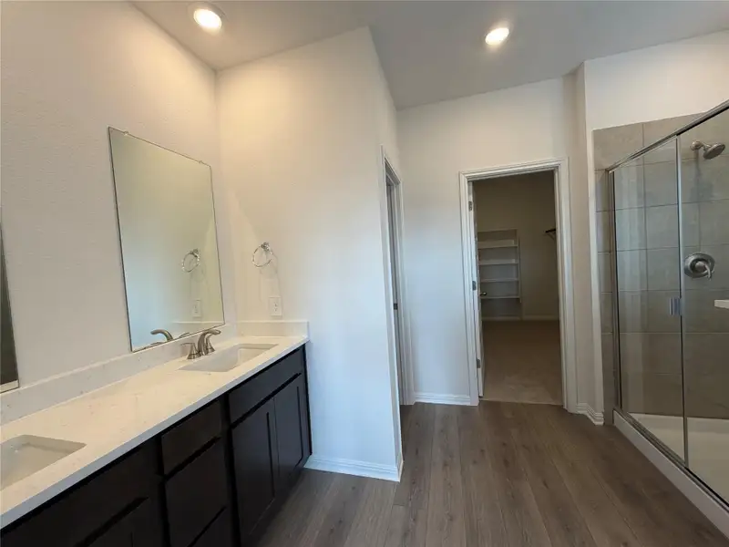Bathroom featuring a spacious closet, dark wood-style floors, double vanity, a shower stall, and recessed lighting