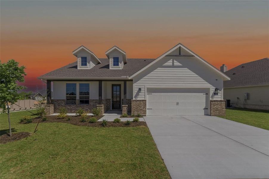View of front facade featuring a front lawn, a porch, an attached garage, concrete driveway, and brick siding