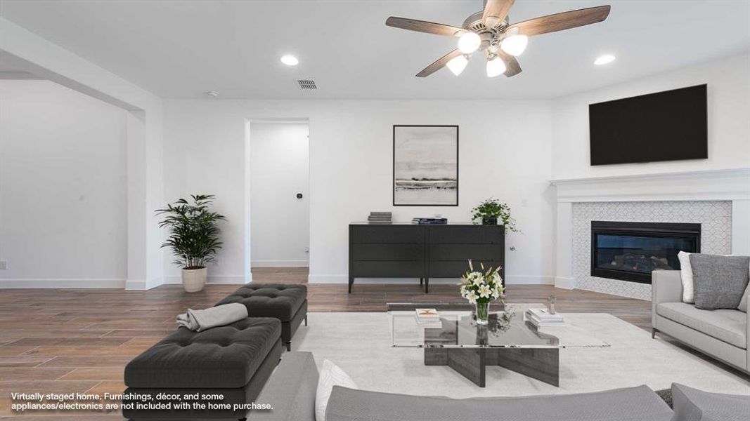 Living room featuring ceiling fan, wood-type flooring, and a fireplace