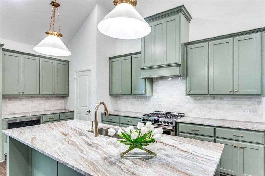 Kitchen featuring decorative light fixtures, green cabinets, tasteful backsplash, and high end range