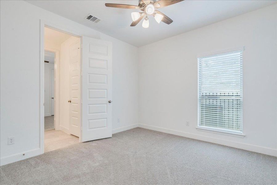 This room features light gray carpet, white walls, and a window with blinds