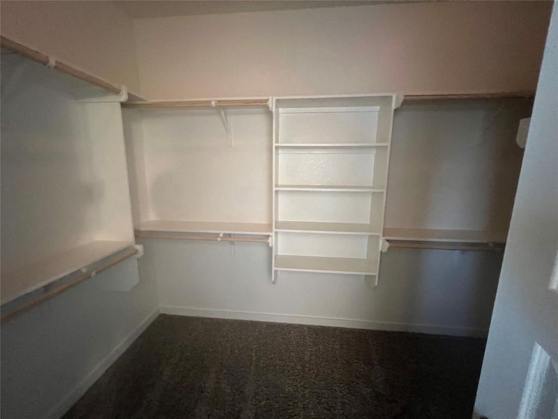 Custom shelving and hanging rods offer ample storage within this organized walk-in closet.